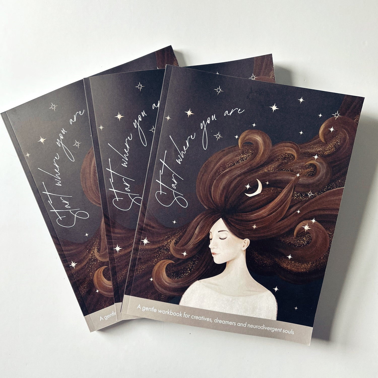 Three notebooks with an illustration of a woman with flowing hair and stars on a dark background.